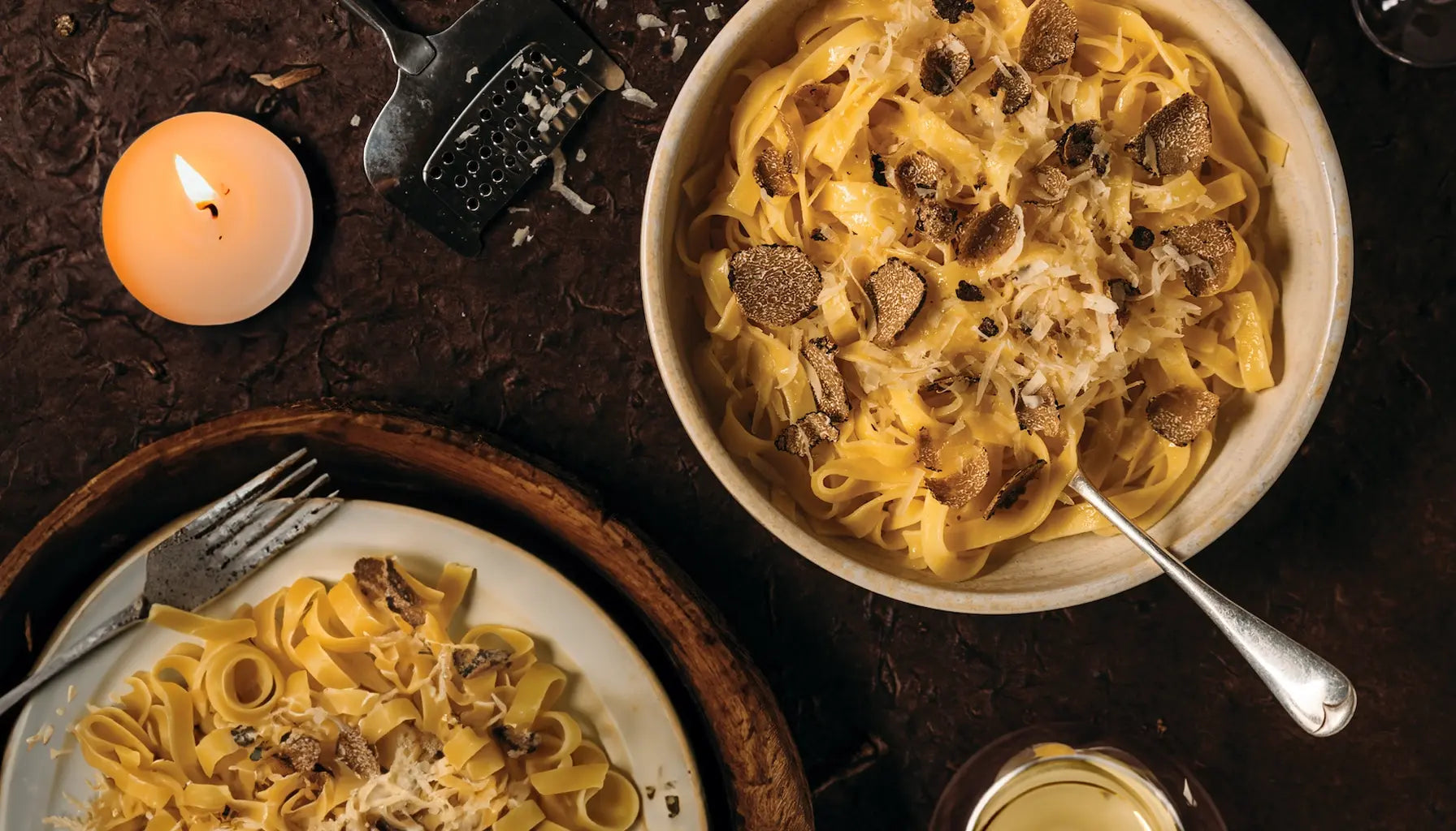 Bandnudeln mit Trüffelscheiben und gehobeltem Parmesan auf zwei Tellern